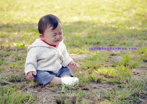 一名儿童独自坐在公园草地上伤心哭泣